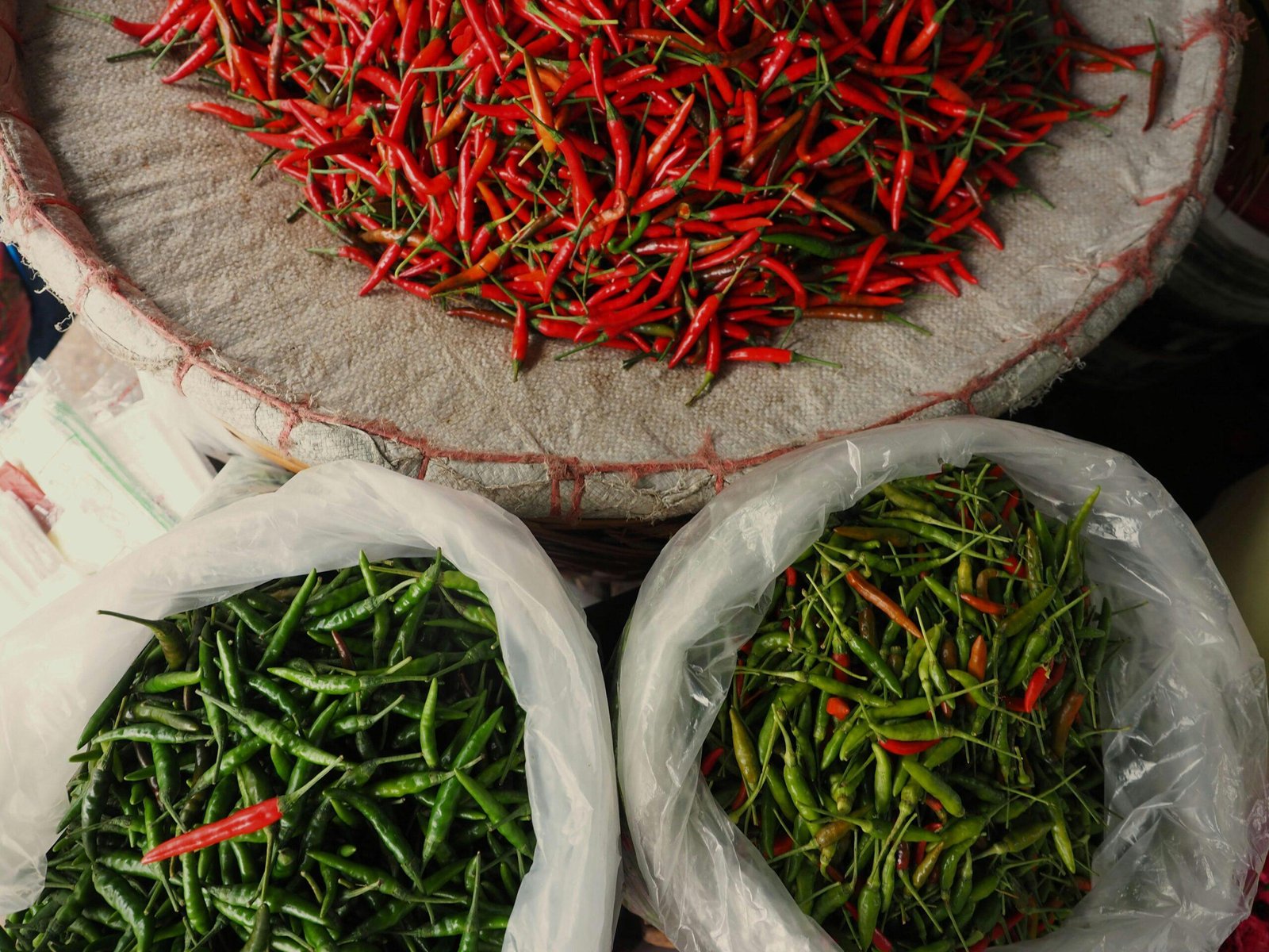 A pile of bags filled with lots of red peppers